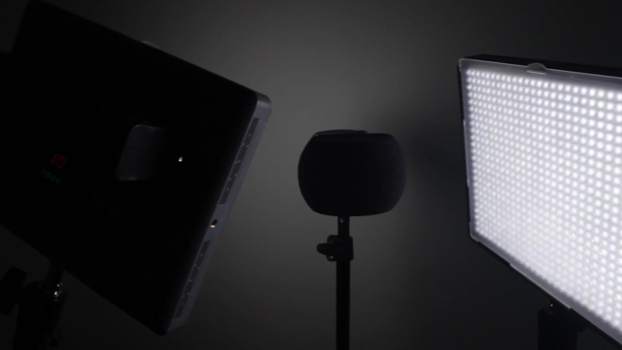 Et dæmpet oplyst studie indeholder et LED-panel og en mikrofonopsætning, ideel til optagelsessessioner eller videoproduktion. Udstyret er placeret for optimal lyd- og lysoptagelse
