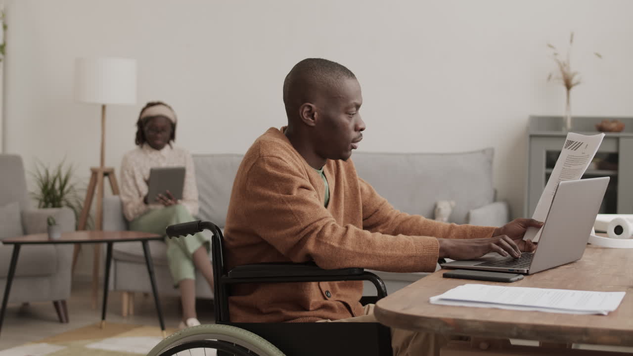 Uomo afroamericano con disabilità che sbriga pratiche a casa