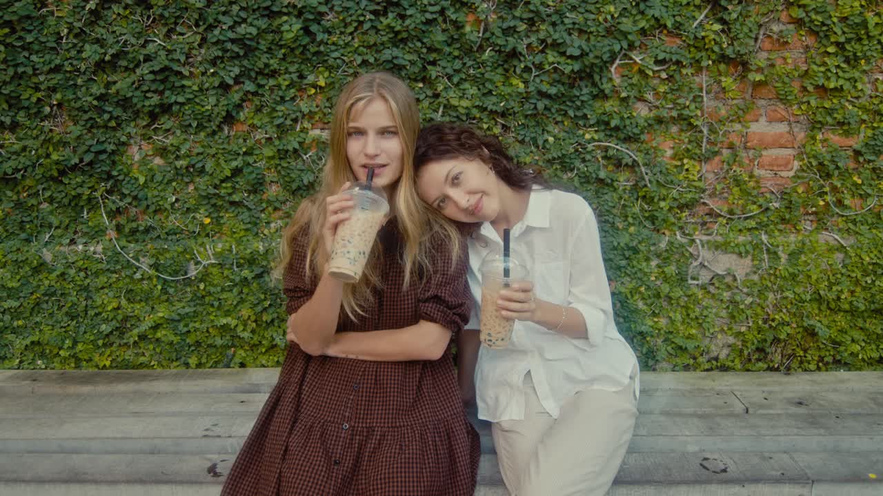 Two women friends enjoying bubble tea outdoors