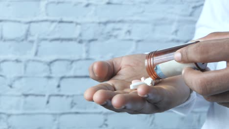 person pouring pills from container into palm