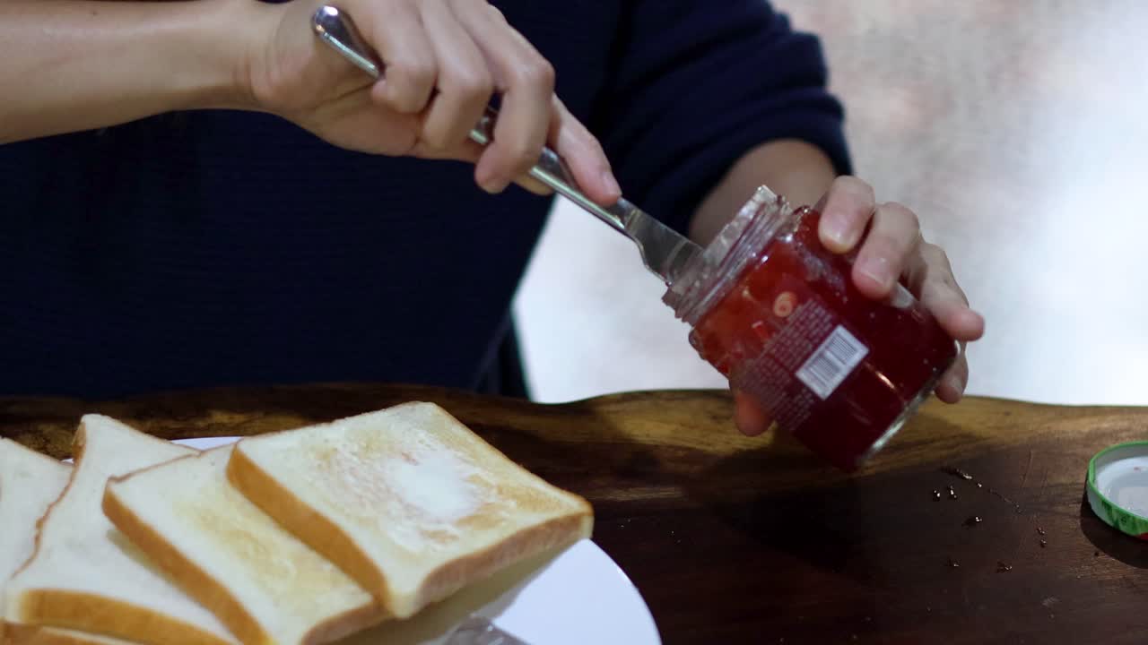 Spreading jam on toast slices for breakfast