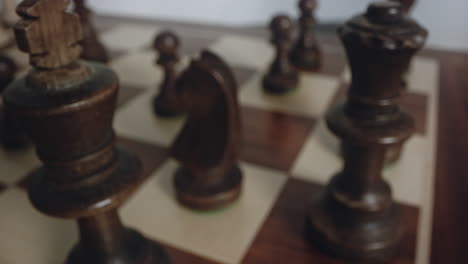 hand moves black wooden king chess piece position as in checkmate, close up