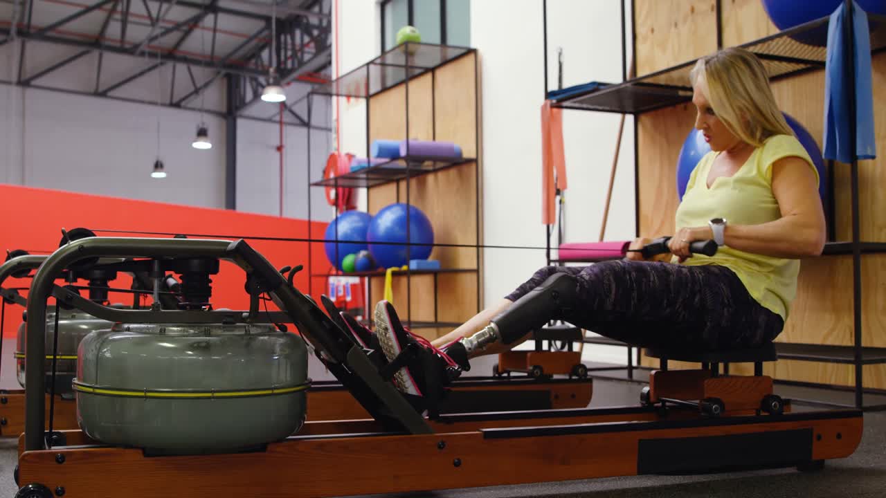 mujer mayor haciendo ejercicio en una máquina de remo en el gimnasio 4k