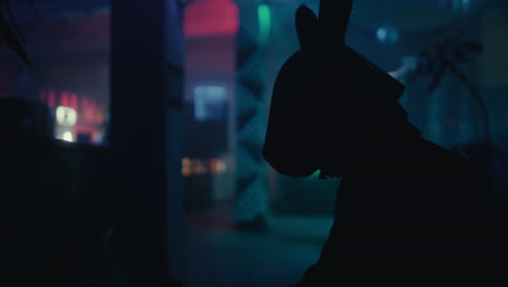silhouette of a person wearing a rabbit mask in a nightclub