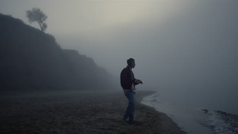 Auriculares-De-Hombre-Relajado-De-Pie-En-La-Playa-De-Niebla.-Chico-Escuchando-Música-En-Auriculares