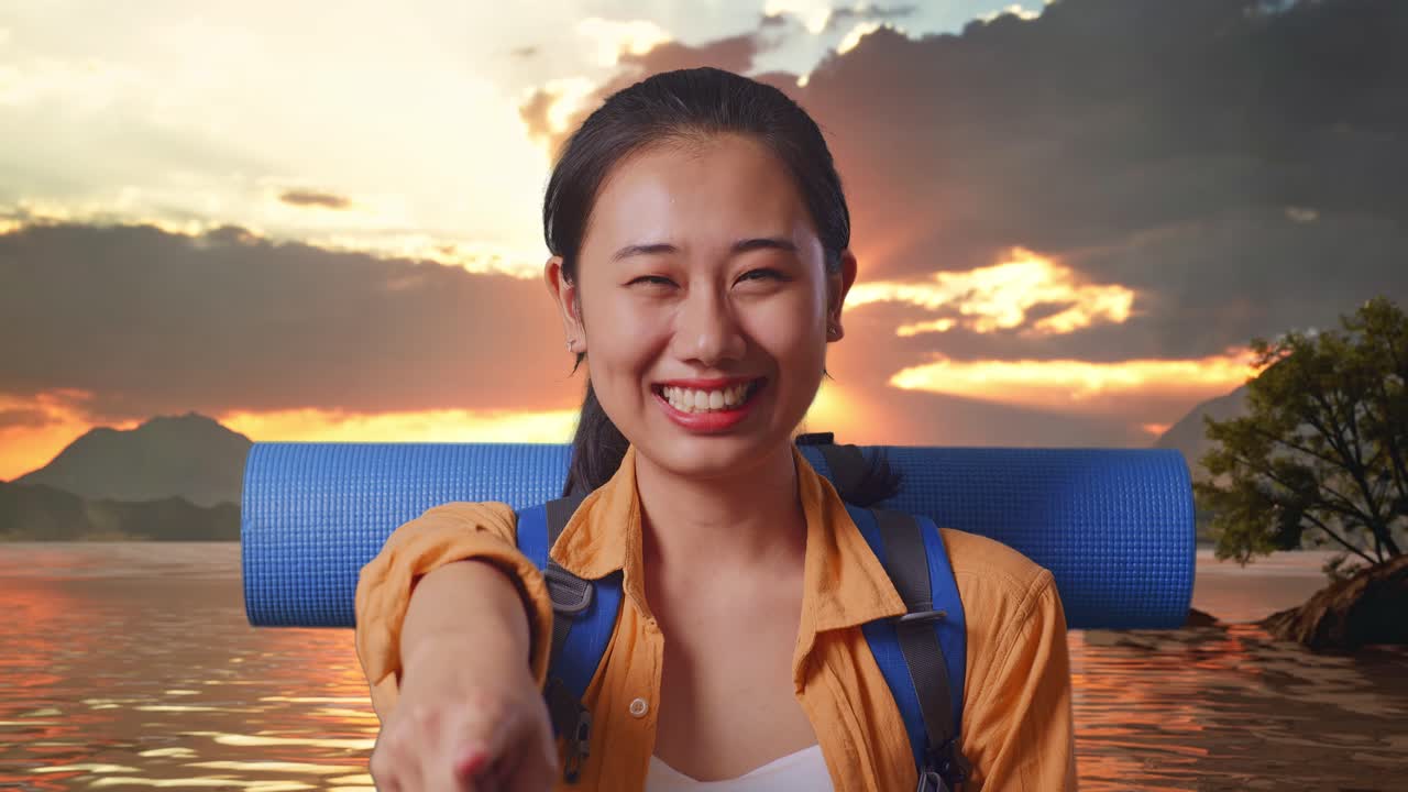 Close Up Of Asian Female Hiker With Mountaineering Backpack Smiling, Touching Her Chest, And Pointing To Camera While Standing At A Lake During Sunset Time