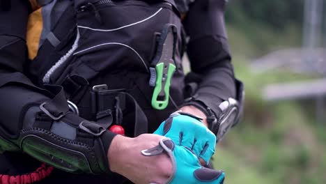 closeup footage of fastening safety suit by wearing technical vest with harnesses. blurred background.