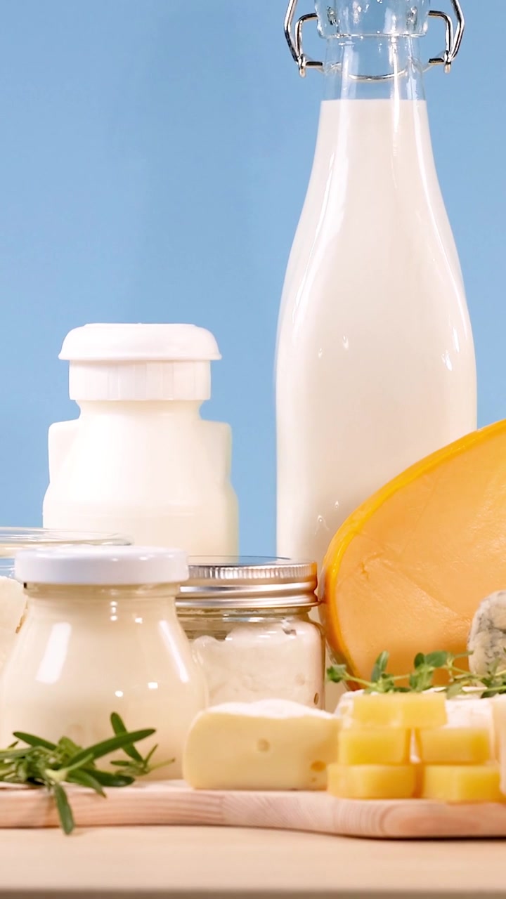 Gros plan vertical de lait frais, de pots de yaourt et de divers fromages sur une surface en bois.