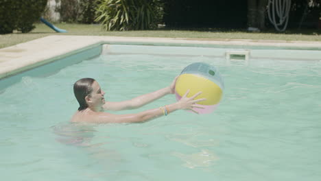 two happy caucasian brothers playing ball in swimming pool