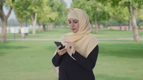 muslim woman using a phone in park