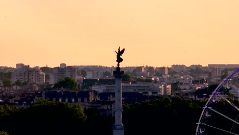 Monumento-De-Columna-De-Girondinos-Con-Escultura-De-Victoria-Alada-Y-Noria-En-Burdeos,-Francia-Durante-La-Puesta-De-Sol,-Toma-Aérea