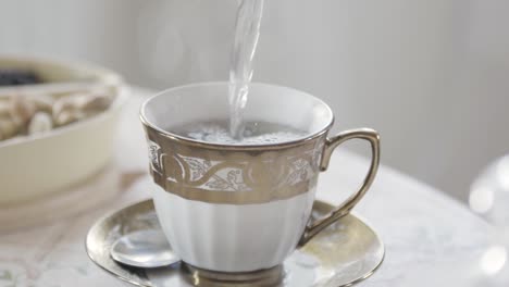 pouring water into a fancy teacup