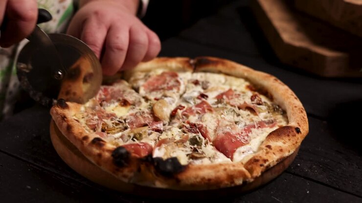 Chef che taglia una deliziosa pizza fatta in casa