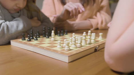 Nahaufnahme-Einer-Mutter-Und-Ihrer-Beiden-Kleinen-Töchter,-Die-Zu-Hause-Schach-Spielen