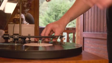 Close-up-view-of-a-vintage-turntable-being-turned-on-and-spinning-by-a-man,-slow-motion-4K