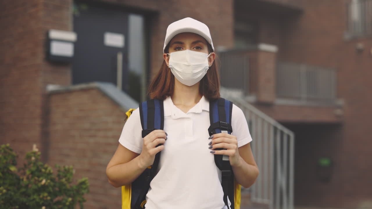 Woman in a mask and uniform delivering package