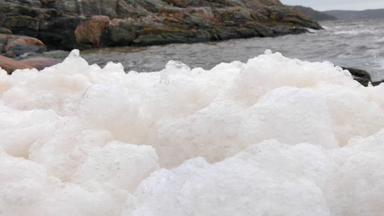 vista cercana de la espuma del mar moviéndose en las olas de la costa de una costa rocosa