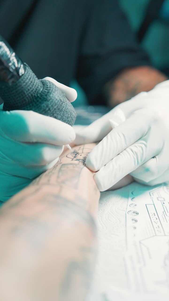 Vertical POV of hand getting ink line tattoo by professional with gloves