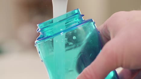 hand filling up a water bottle from a kitchen tap