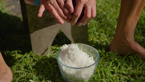 woman shredding the meat out of a coconut shell by hand - isolated slow motion