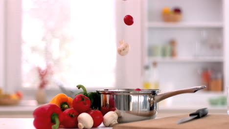 cherry tomatoes and mushrooms falling in saucepan in kitchen
