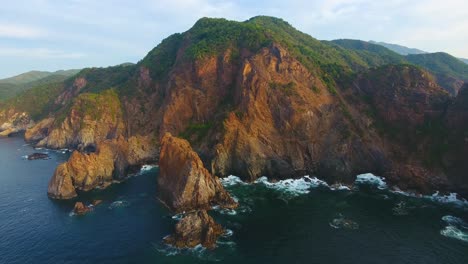 Mountainous-cliff-face-along-the-coast-of-Mexico-straight-down-into-the-dark-blue-ocean-water-of-Carrizal-anchorage-during-golden-hour