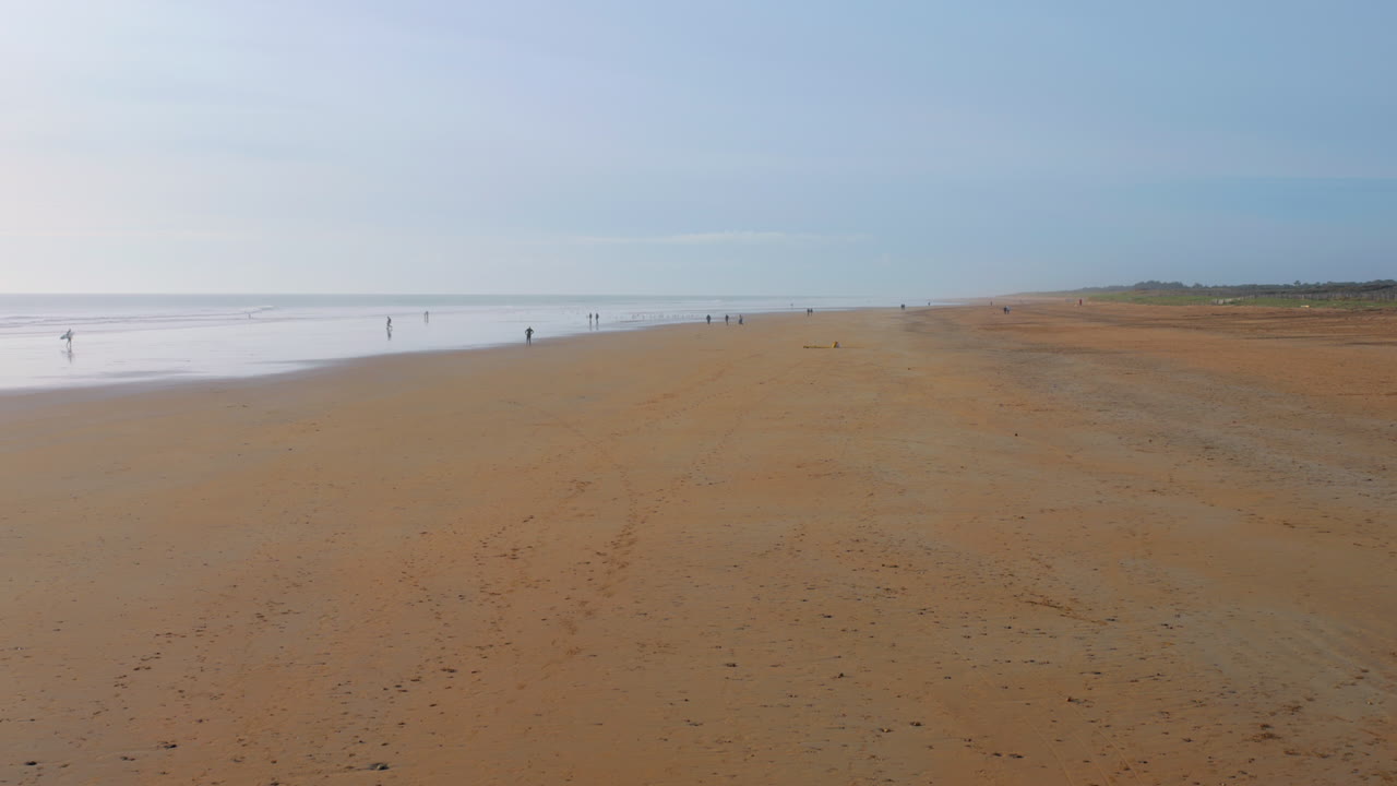 프랑스 세인트 장 드 몬트 (saint-jean-de-monts) 의 넓은 모래 해변, 멀리 있는 인물들과 부드러운 파도가