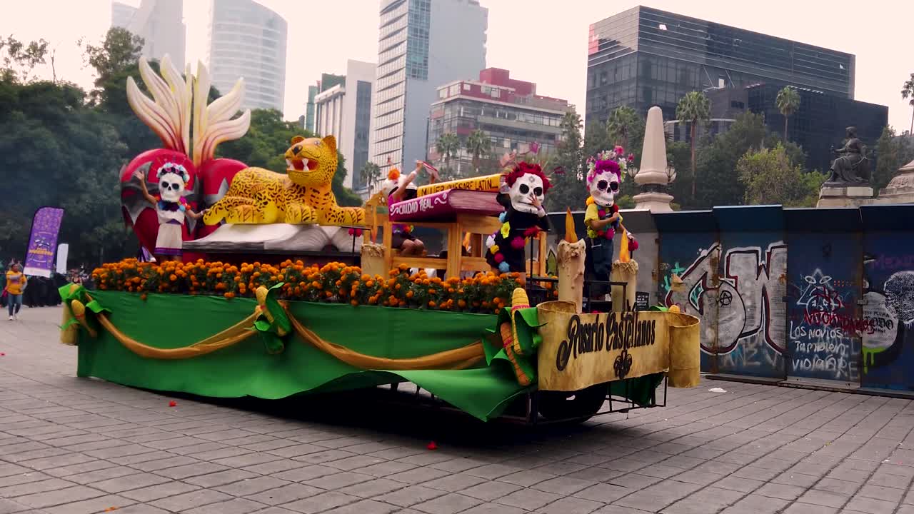 Tracking shot of a float honoring Mexican writer Rosario Castellanos during the Day of the Dead parade along Paseo de la Reforma in Mexico City
