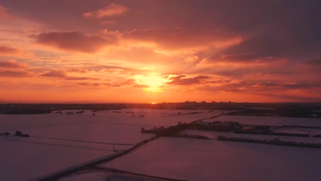 Toma-Aérea-Asombrosa-Puesta-De-Sol-Con-Campos-De-Nieve-Sombreados-Oscuros-Debajo