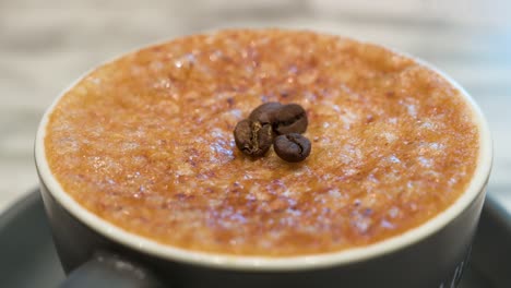 Eine-Tasse-Brûlée-Kaffee-Mit-Einer-Kristallisierten,-Harten,-Spröden-Schicht-Aus-Karamell-Und-Kaffeebohnen