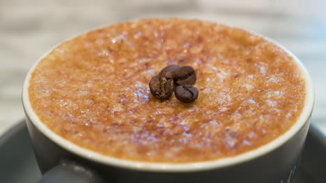 una taza de café brulée con una capa dura y quebradiza cristalizada de caramelo y granos de café