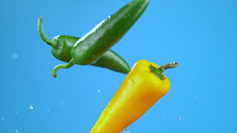 Yellow-and-green-chili-bell-peppers-launched-in-air-with-water-droplets,-vegetables-for-cooking