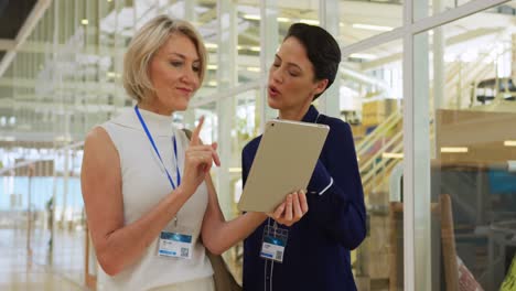 mujeres de negocios usando una tableta en un vestíbulo de una conferencia