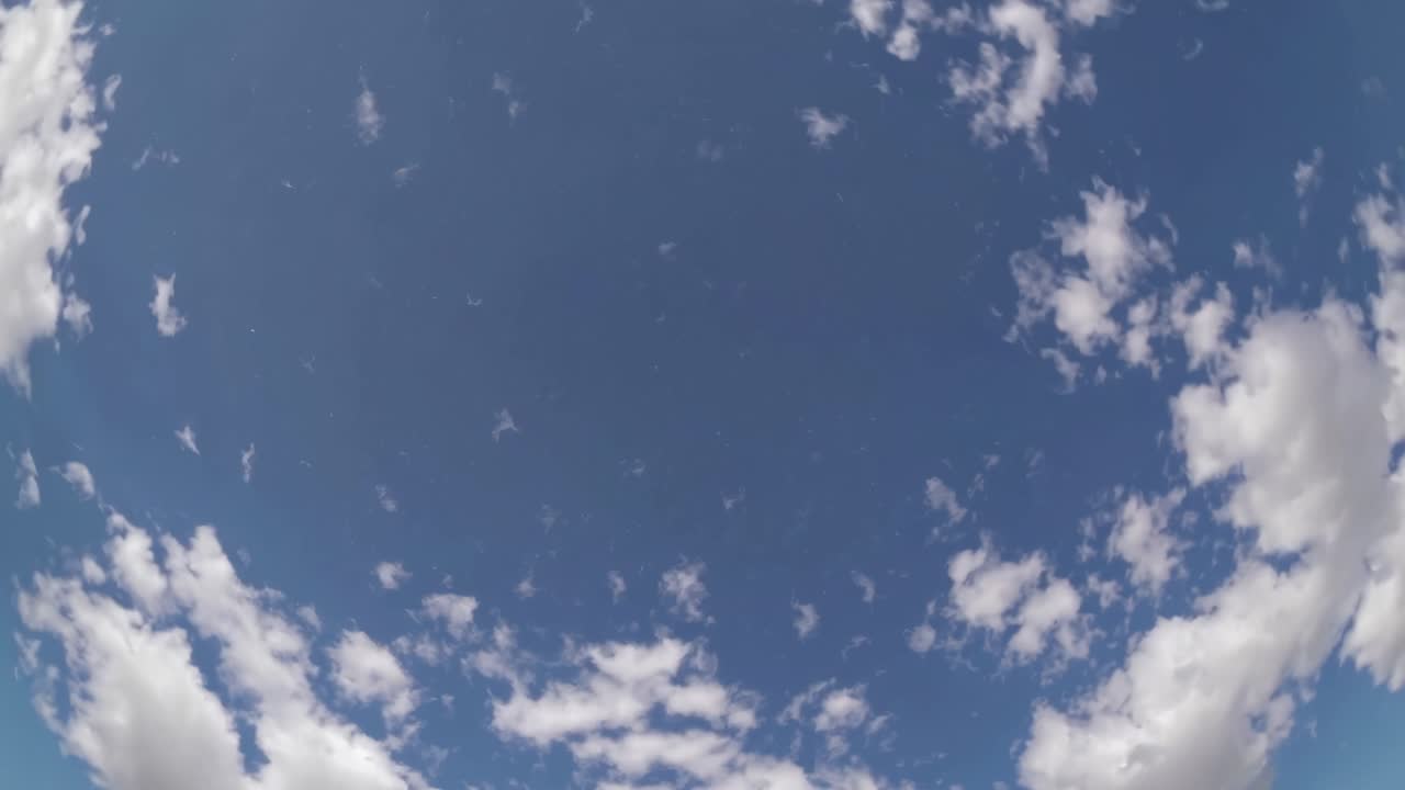A fisheye lens captures a vast blue sky with scattered clouds, creating a dynamic, immersive video