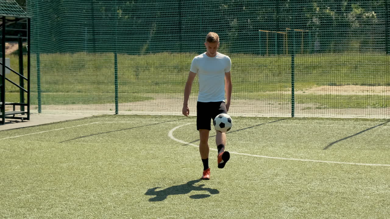 화창한 날 10일 거리 축구 경기장에서 공을 가지고 프리스타일 트릭을 훈련하는 젊은 축구 남자