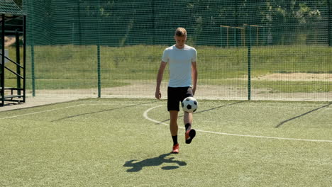 a young soccer man training freestyle tricks with the ball on a street football pitch on a sunny day 10