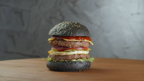 Black-Burger.-Ein-Burger-Mit-Schwarzen-Brötchen,-Saftigen-Marmor-Rindfleischscheiben,-Käse,-Frischem-Salat-Und-Barbecuesauce.