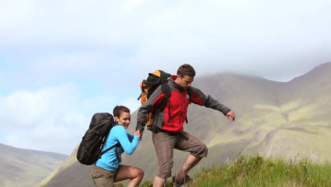 Couple-hiking-up-an-incline-together-and-pointing