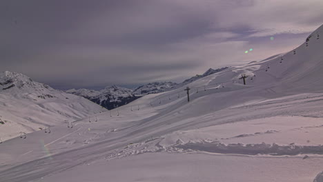 thick fresh snow on slope at ski resort with chair lift - clouds moving over white winter landscape