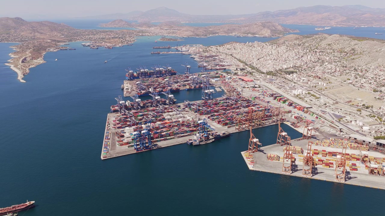 High aerial view of a bustling commercial seaport with container ships docked at the terminal, showing cranes loading and unloading cargo for global shipping and logistic transportation