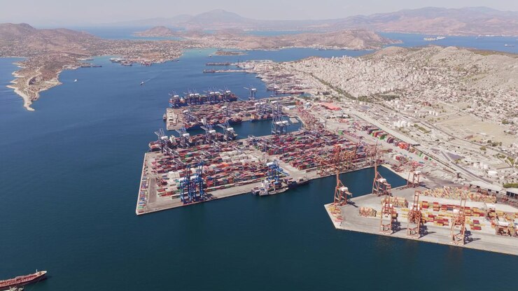 High aerial view of a bustling commercial seaport with container ships docked at the terminal, showing cranes loading and unloading cargo for global shipping and logistic transportation