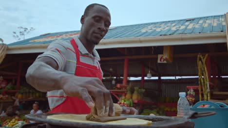 street food vendor making chapati in kampala, uganda africa