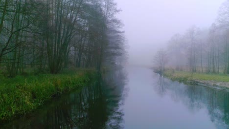 Segeln-Entlang-Eines-Dunklen,-Nebligen-Flusses-Mitten-Im-Wald