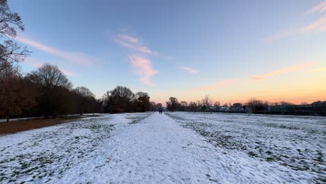 Point-of-view-walking-through-snow-covered-field-in-nature-at-sunset