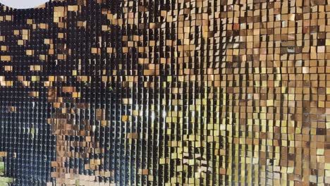 abstract background with flickering metallic or plastic particles wall, same size of shape of particles, real footage, a wall of golden sparkles spiked in the wind