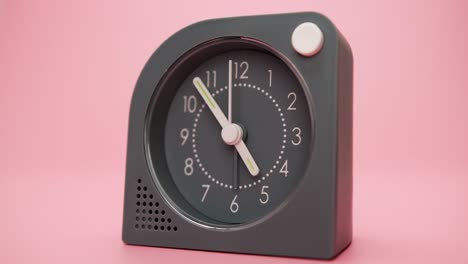 reloj de alarma aislado en un fondo rosa, el tiempo comienza a caminar a las nueve.