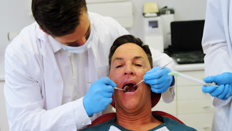 Dentists-examining-a-male-patient-with-tools