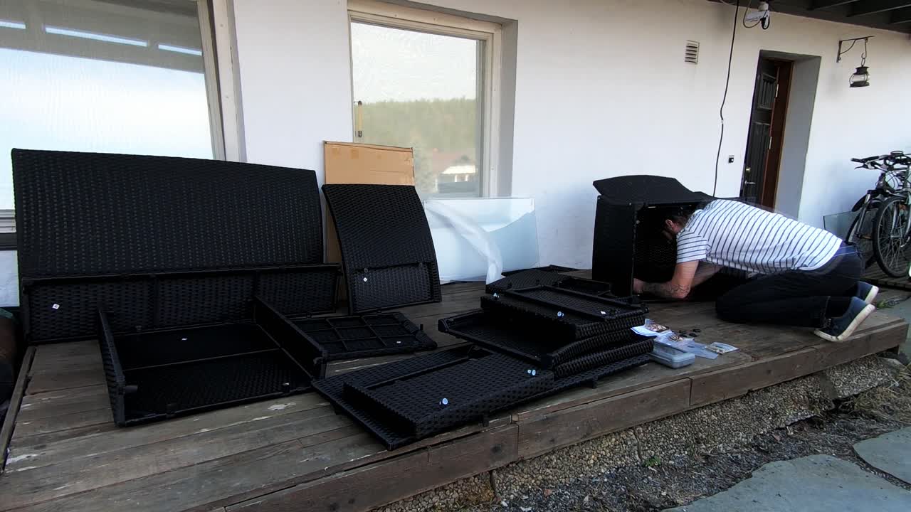 Man assembling furniture outside the house on the terrace in timelapse