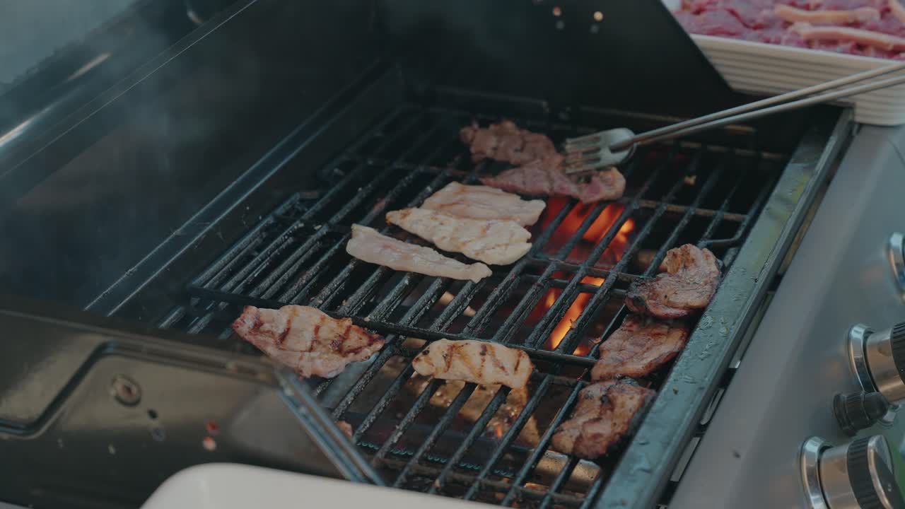 닳아 해진 바비큐 그릴 위에서 지글거리는 뜨거운 고기가 요리되고 있어요.