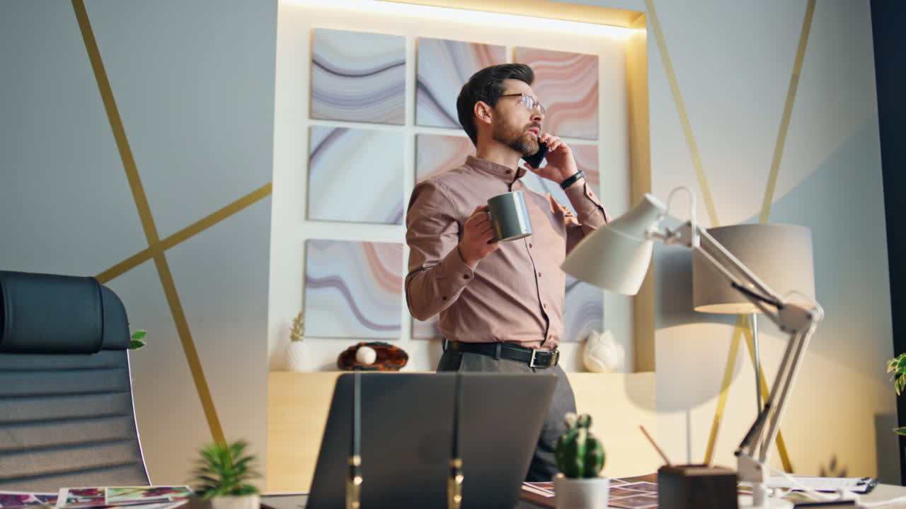 Business man calling drinking coffee at company workplace. Worker talking phone.